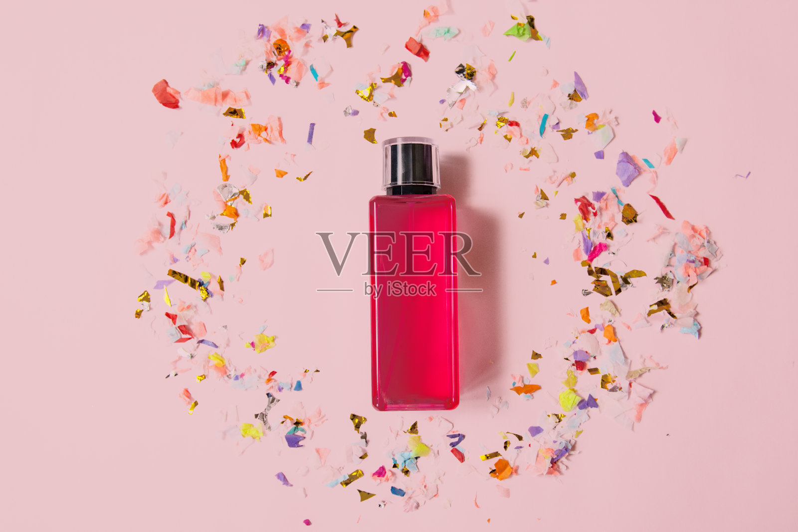 化妆品包装设计概念或模型与空白透明瓶与粉红色香水在粉红色的表面被节日装饰包围。照片摄影图片