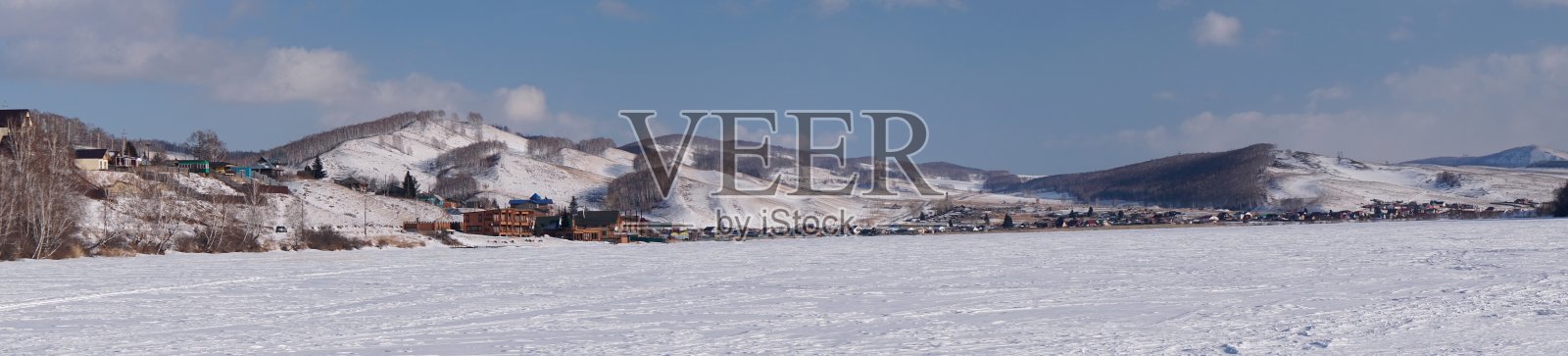 Parnaya村位于冰冻的大湖岸边，在一个冬日的森林山丘的背景下。克拉斯诺雅茨克地区。俄罗斯。照片摄影图片