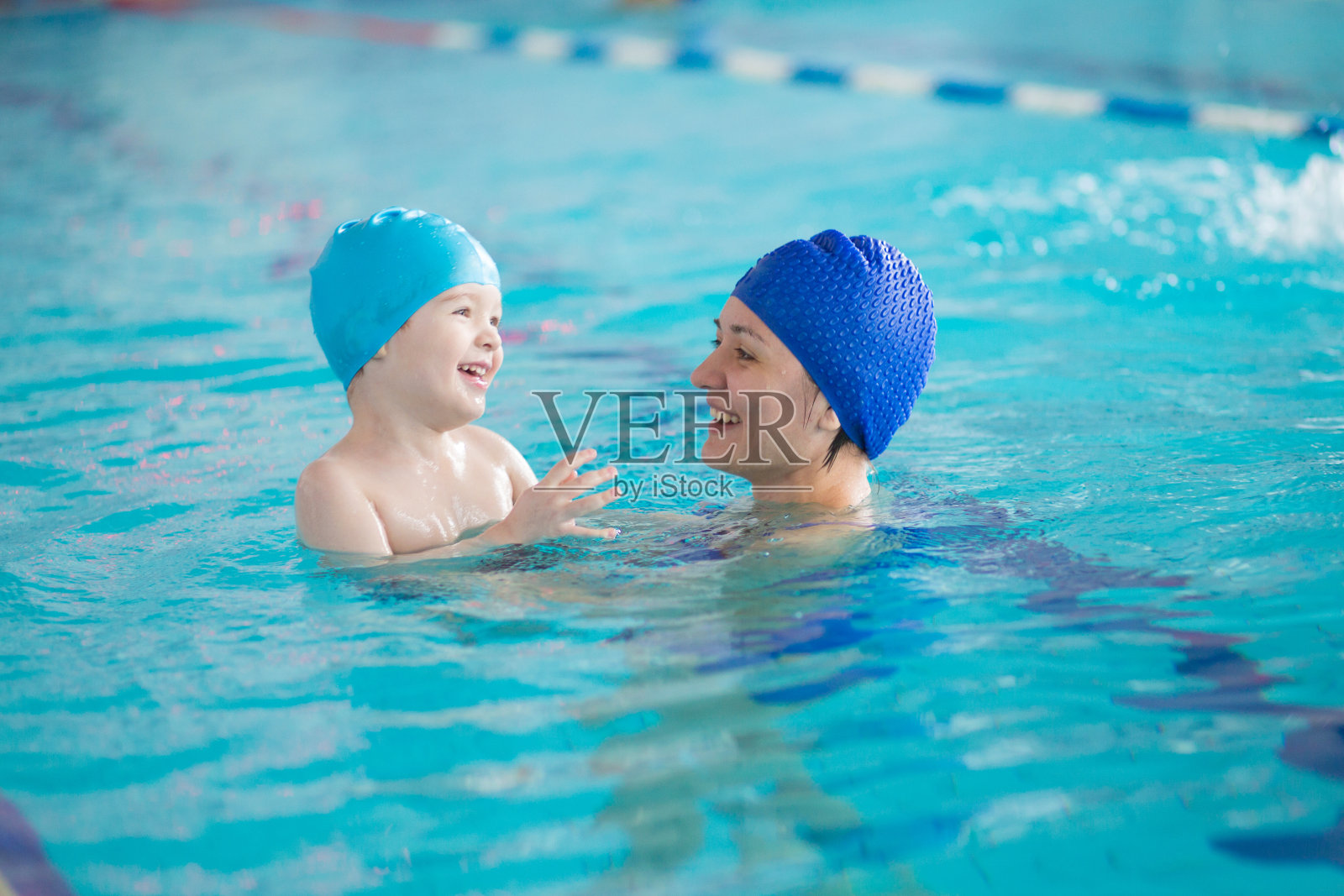 宝宝和妈妈一起在游泳池里学习游泳。妈妈教儿子游泳照片摄影图片