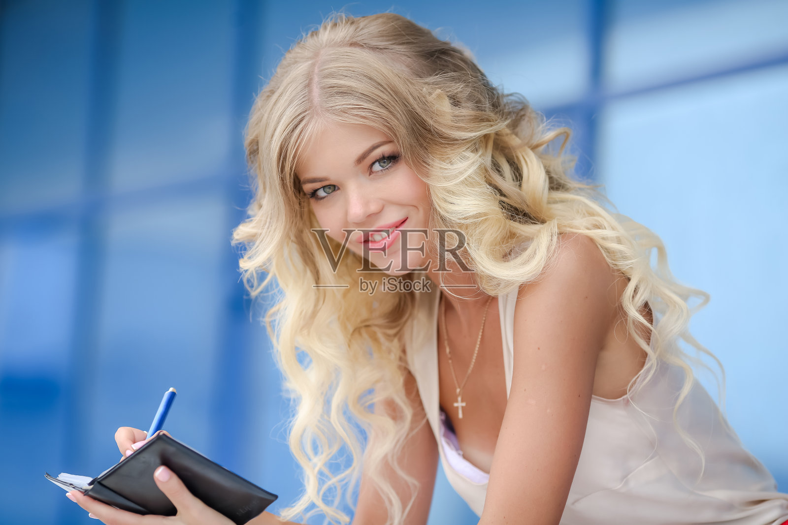 一个卷发的金发女人的肖像，她手里拿着一个笔记本照片摄影图片