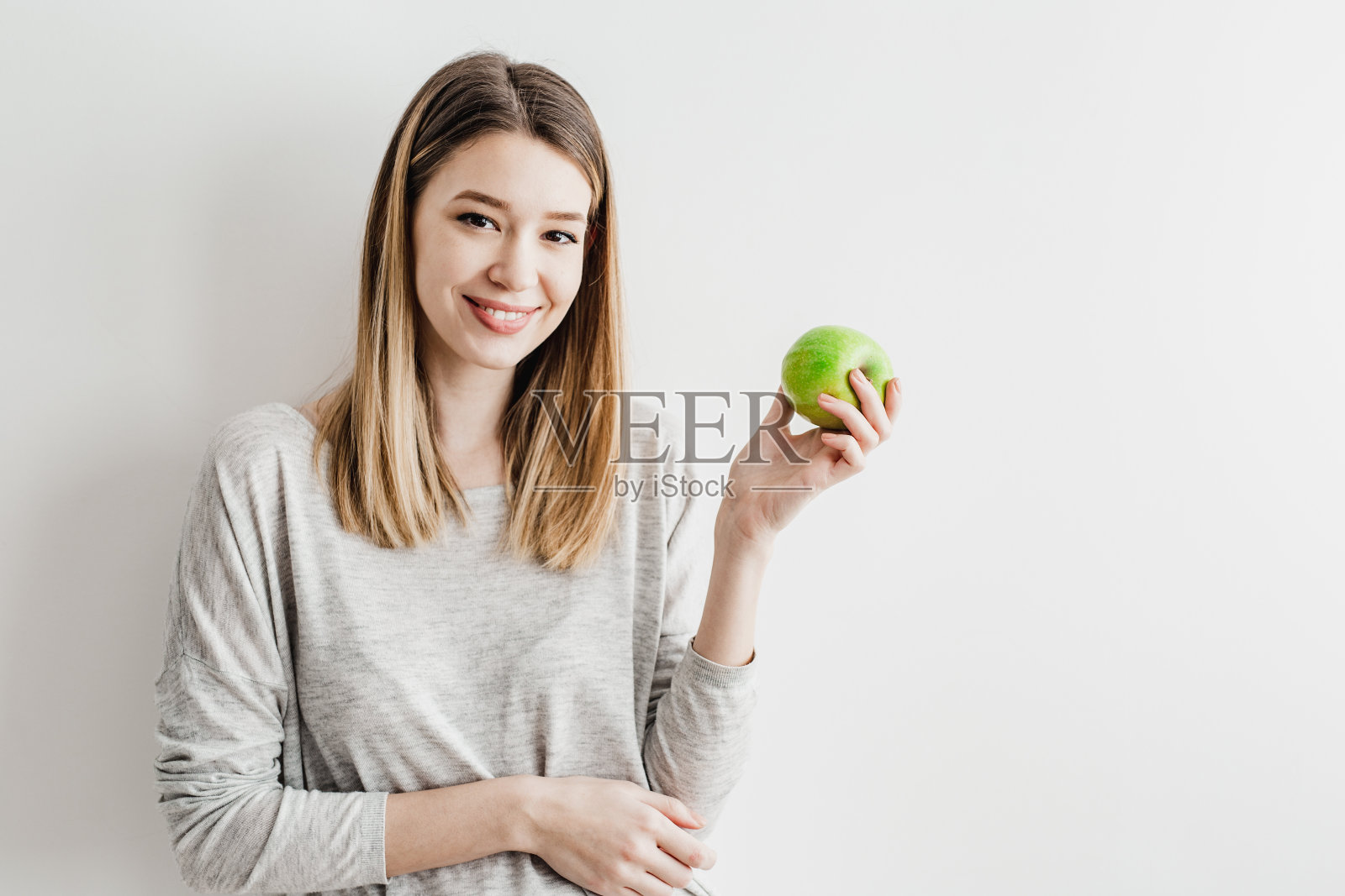 一位年轻女子手里拿着一个绿色的苹果作为健康的象征照片摄影图片