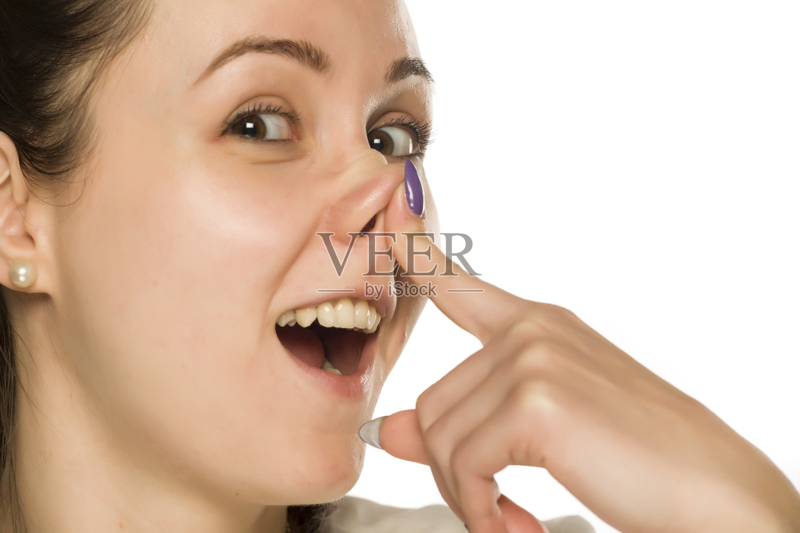 一个有趣的微笑的女人在白色的背景上触摸她的鼻子照片摄影图片