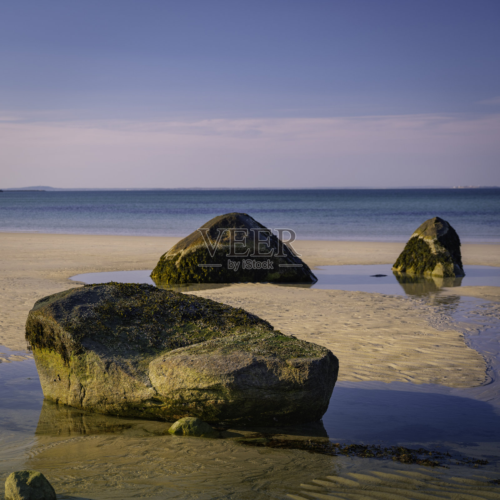 在低潮的背景下，在色彩柔和的沙滩上放置三个像禅宗一样的巨石照片摄影图片