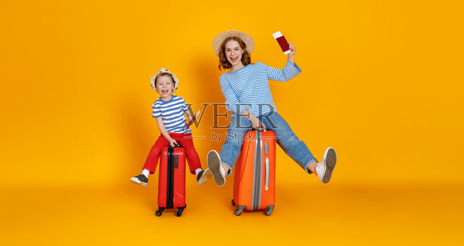 旅途愉快!家庭旅行者母亲和孩子手提箱，票和护照在黄色背景照片摄影图片