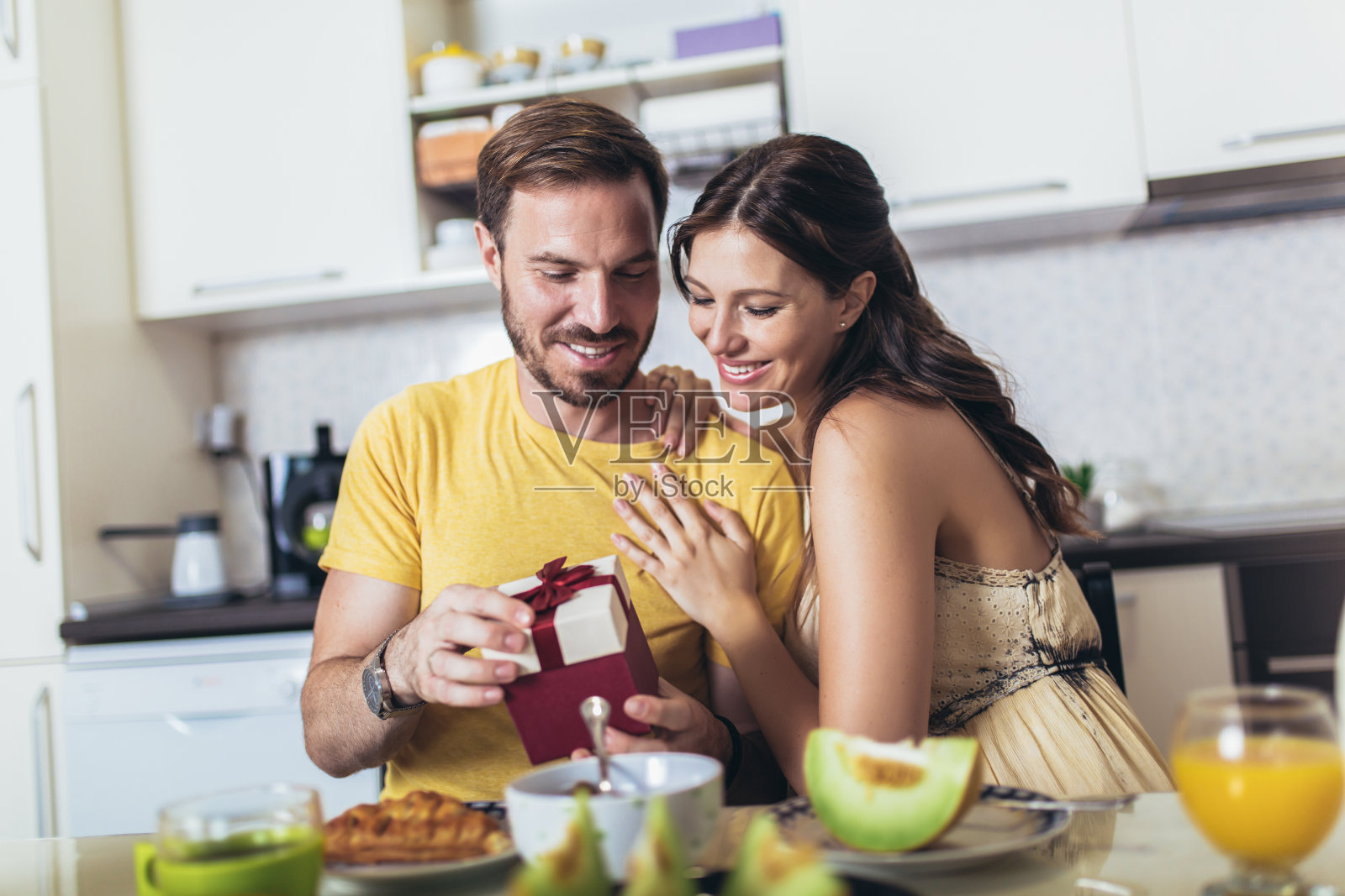 快乐快乐的男人惊喜他的女朋友在家里的厨房当早餐的礼物照片摄影图片