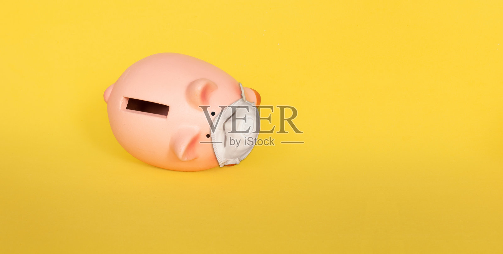 跌落的小猪储蓄罐戴着面具在黄色的背景照片摄影图片