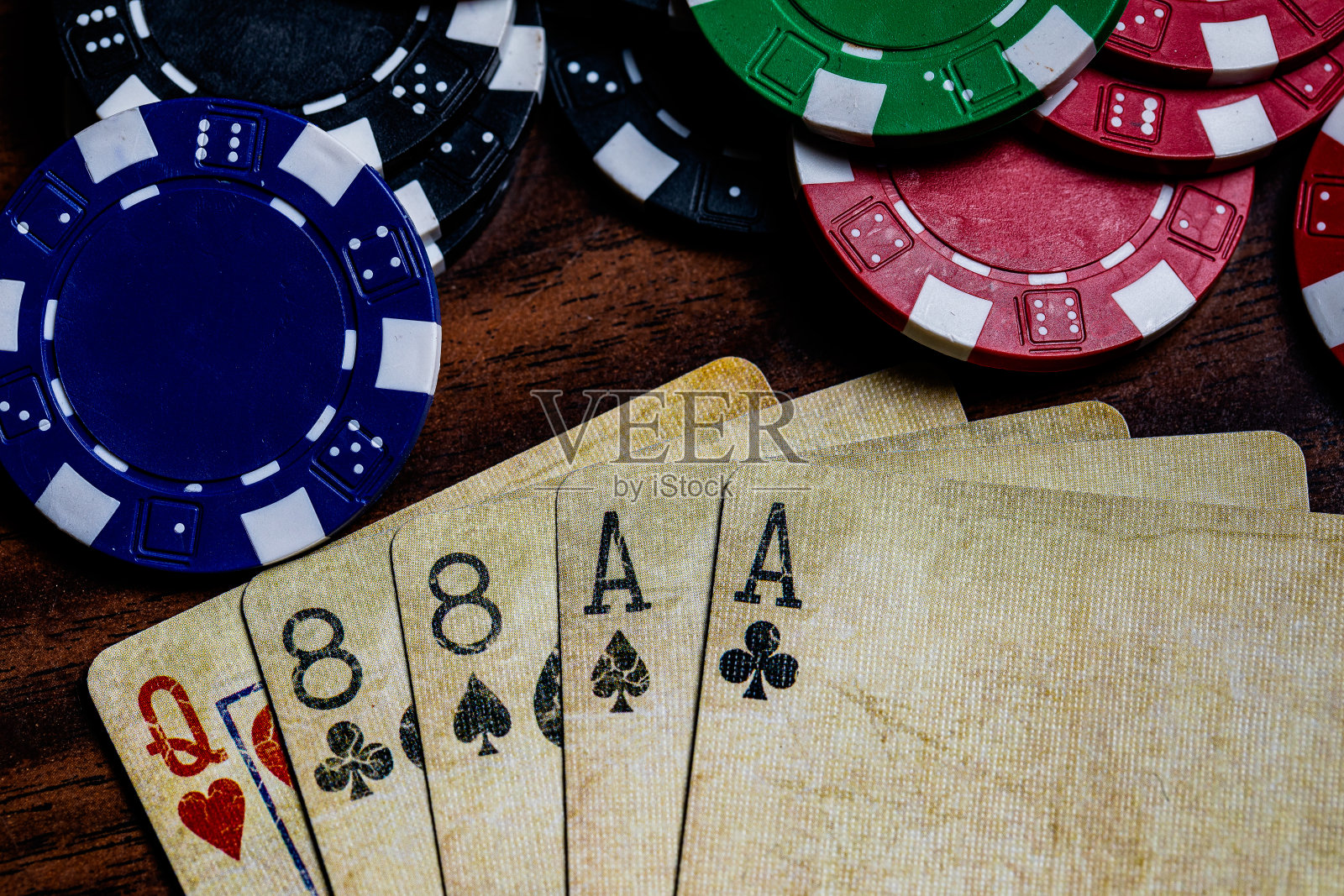 死亡之人的手顶部宏与复古的使用过的扑克牌和扑克筹码在木桌子上，以柔和的暖色调。《梅花a》的副本照片摄影图片