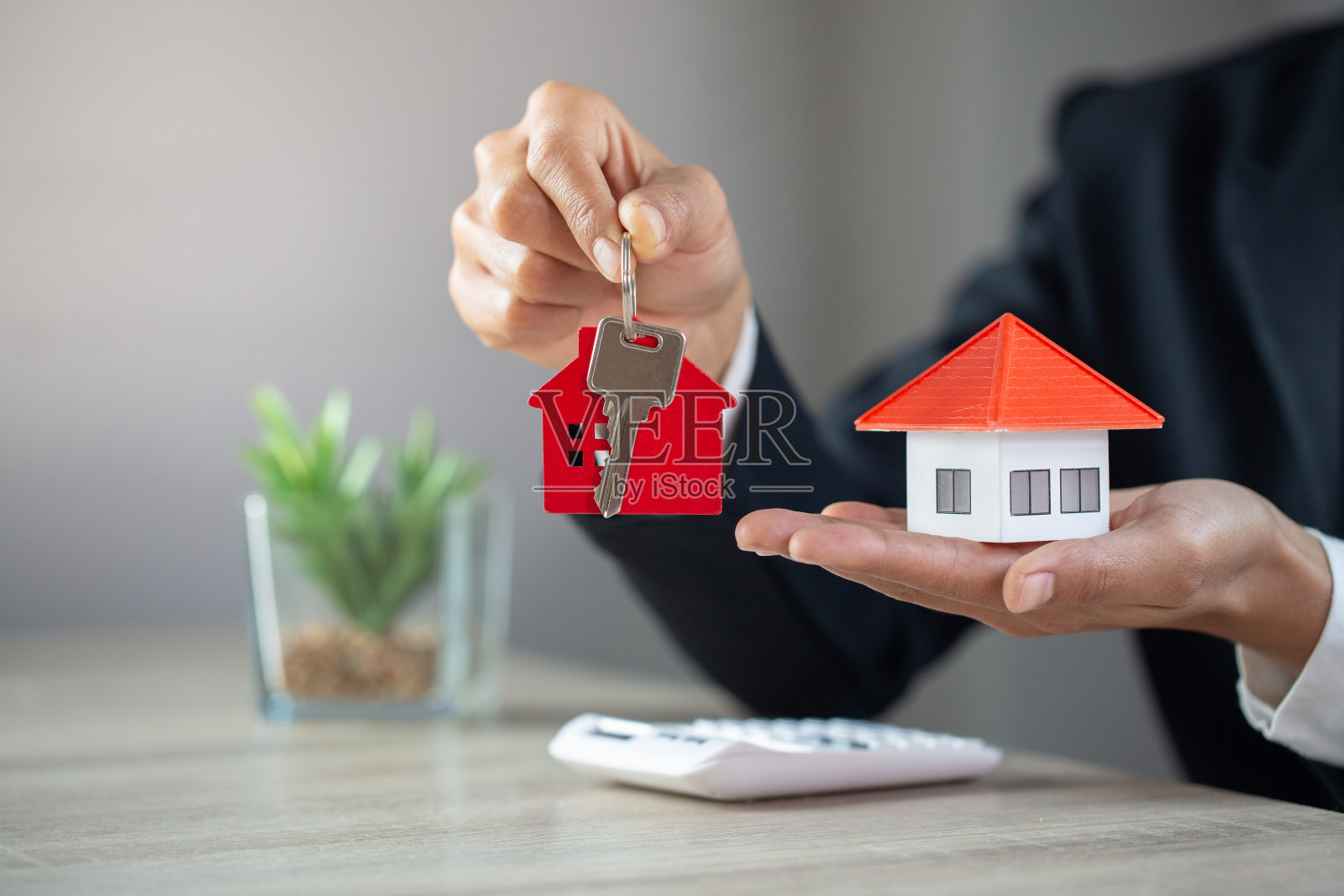 房地产经纪人持有房屋模型和钥匙，客户签订购房合同，保险或贷款房地产。照片摄影图片
