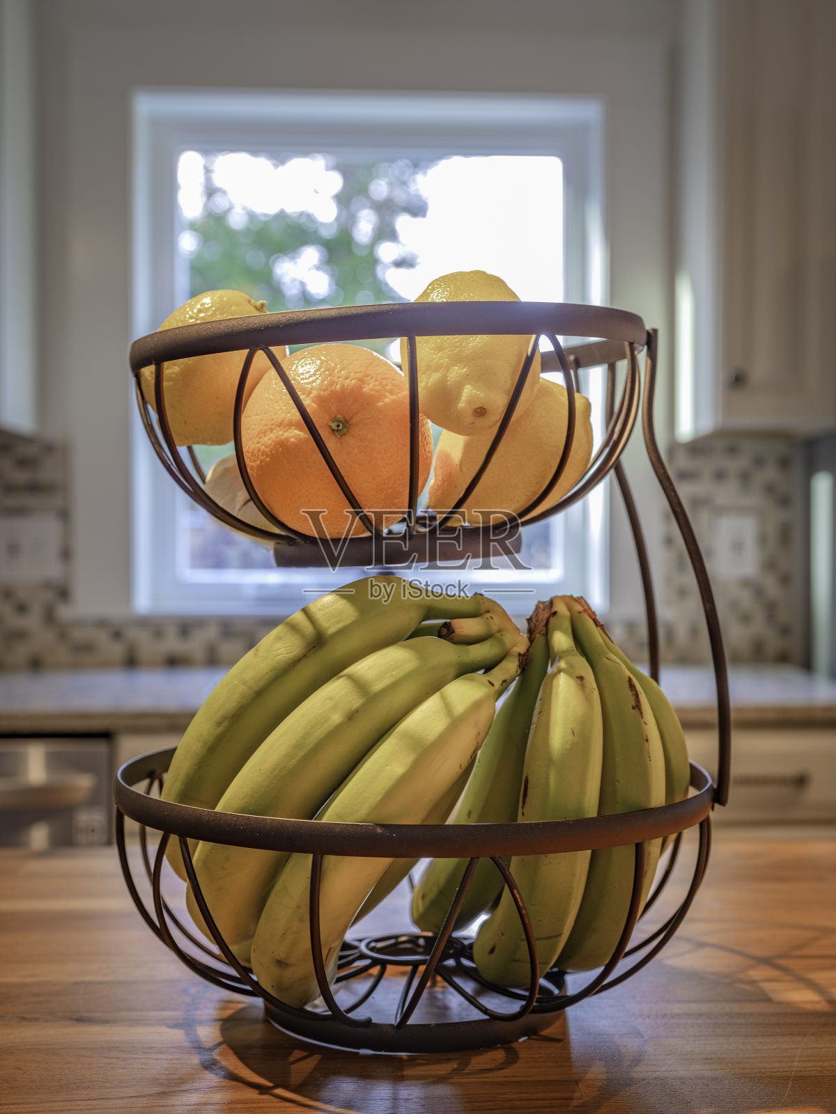 两层乡村水果篮，香蕉，橘子和柠檬在厨房柜台上照片摄影图片