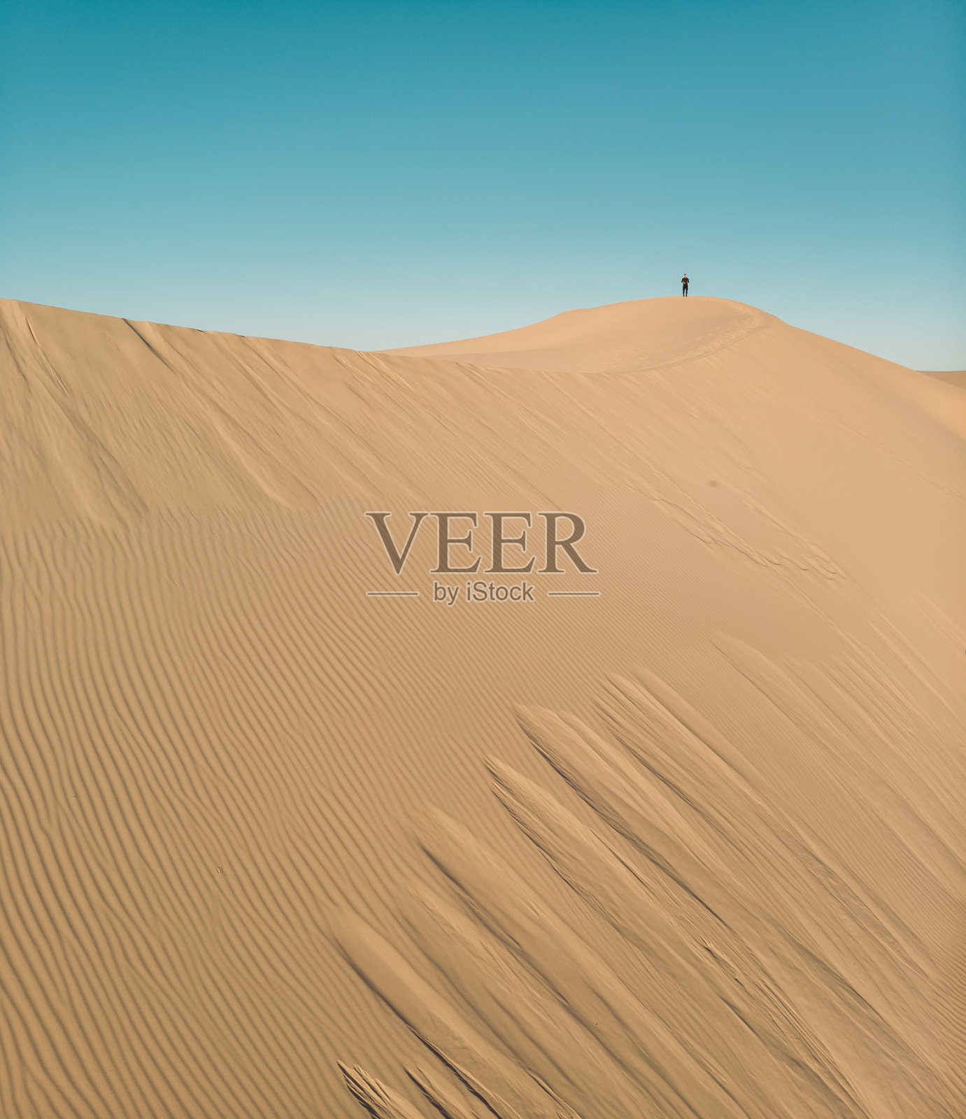 男子站在巨大的纹理沙丘顶部的无人机照片摄影图片
