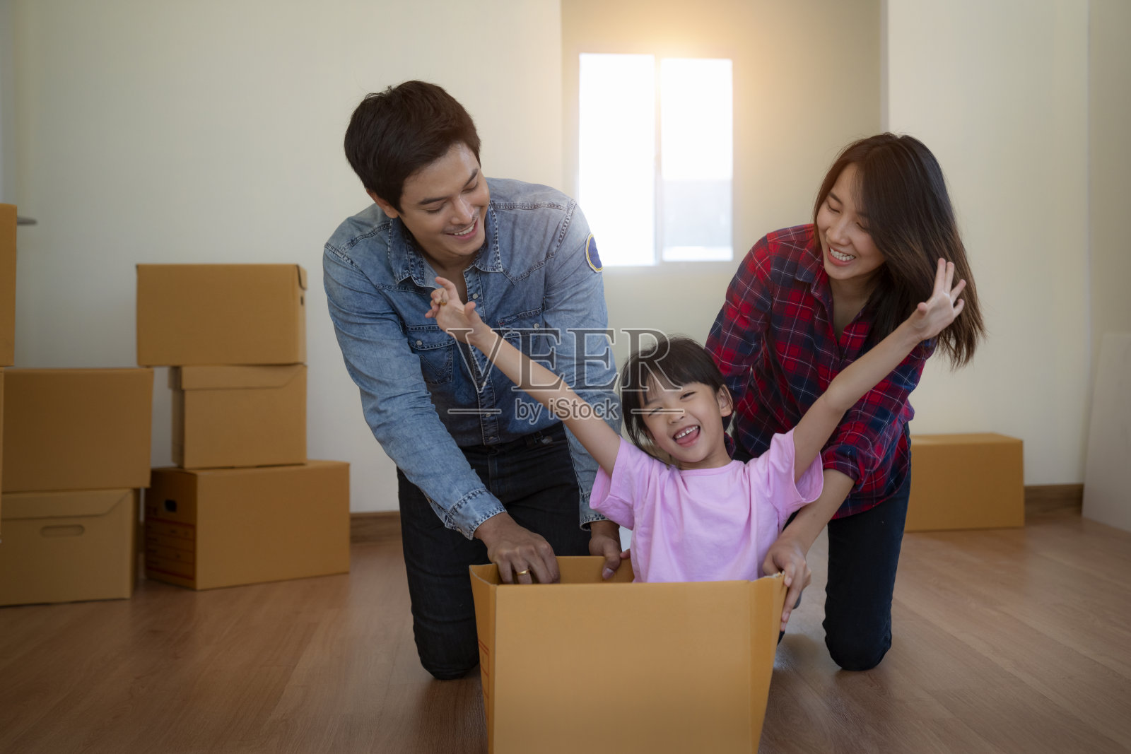 快乐的亚洲家庭与纸箱在新房子搬家日。照片摄影图片