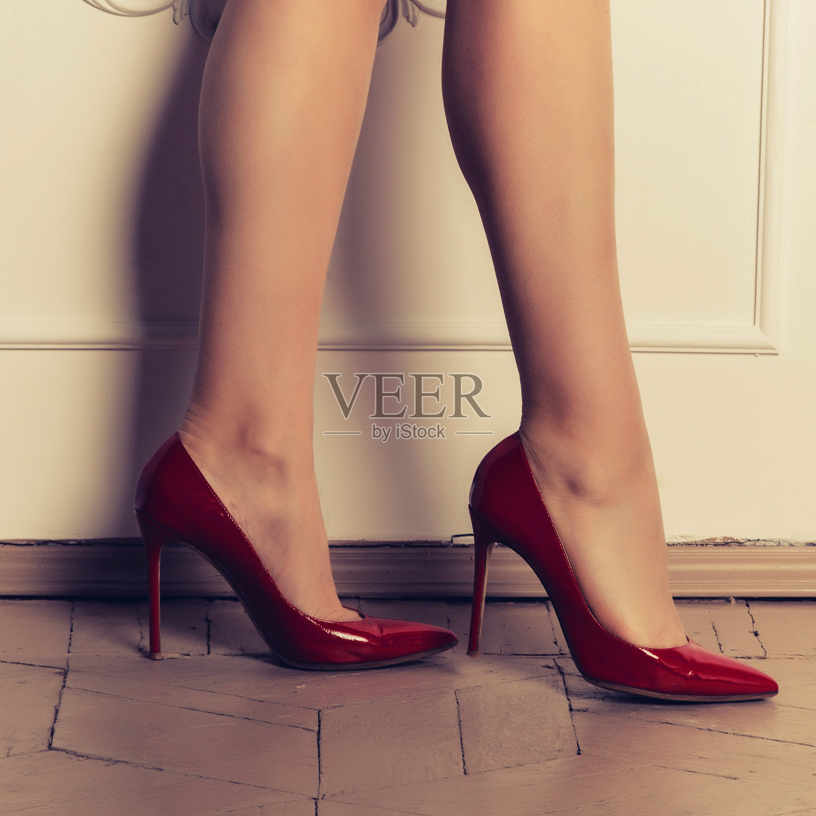性感女人的腿在红色高跟鞋在镶木地板附近的白色墙壁照片摄影图片