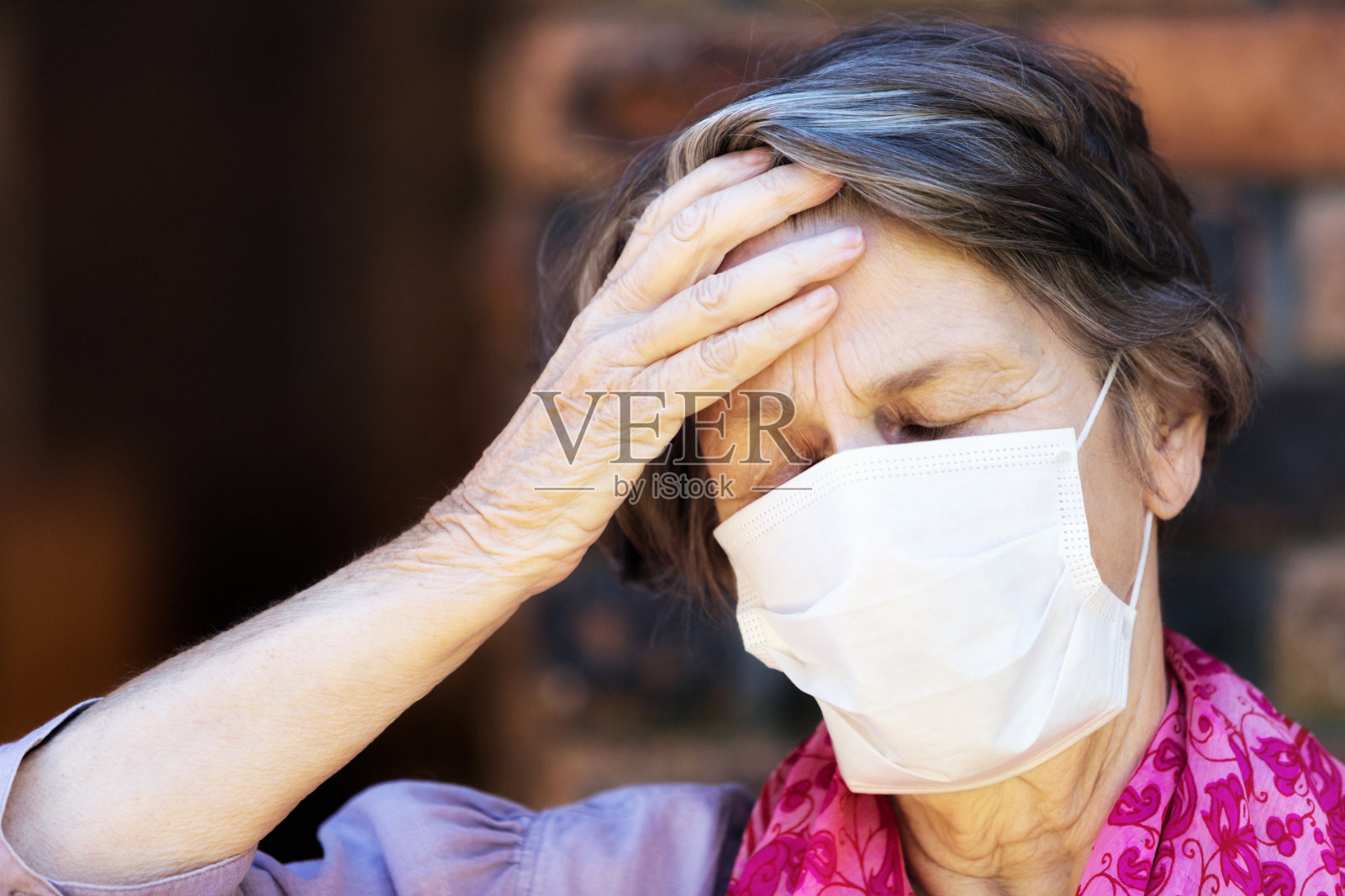 在COVID-19冠状病毒疫情期间佩戴外科口罩的老年妇女照片摄影图片