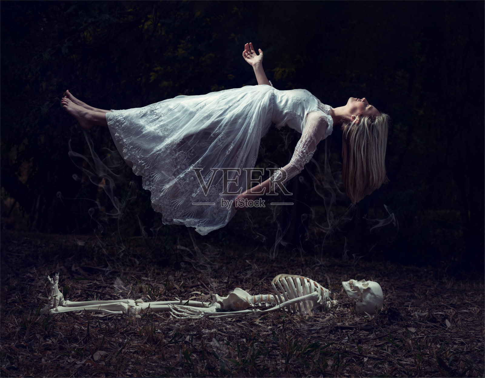 一个女人从枯叶上的骷髅中升起的飘浮画面照片摄影图片