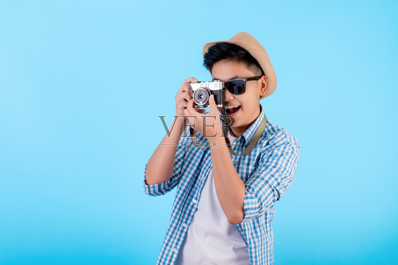 可爱的业余亚洲摄影师微笑着在蓝色的背景下拍照。照片摄影图片