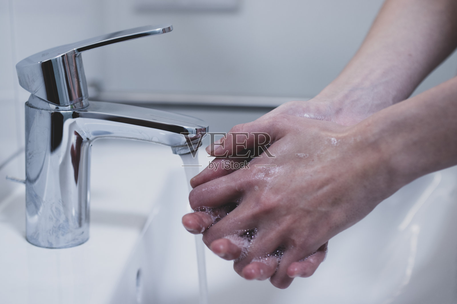 一个女人在水槽里用水和肥皂洗手照片摄影图片