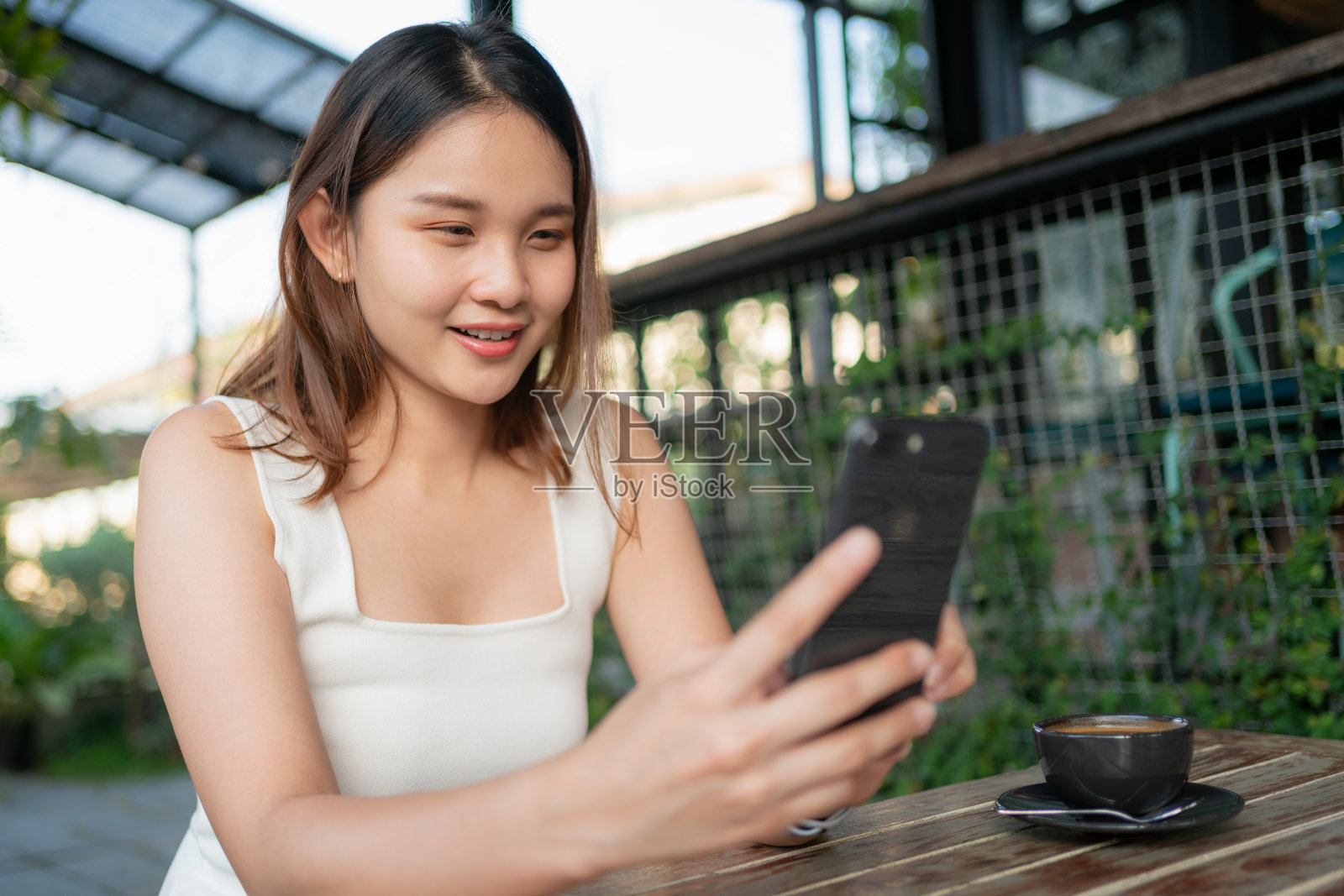 美丽的亚洲女人使用智能手机快乐和放松在咖啡店。企业女性的概念照片摄影图片
