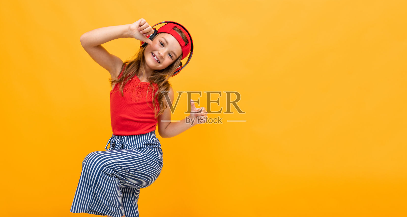 一个穿着红色t恤和牛仔裤的女学生在黄色背景上热情地跳舞，充满感情的肖像照片摄影图片