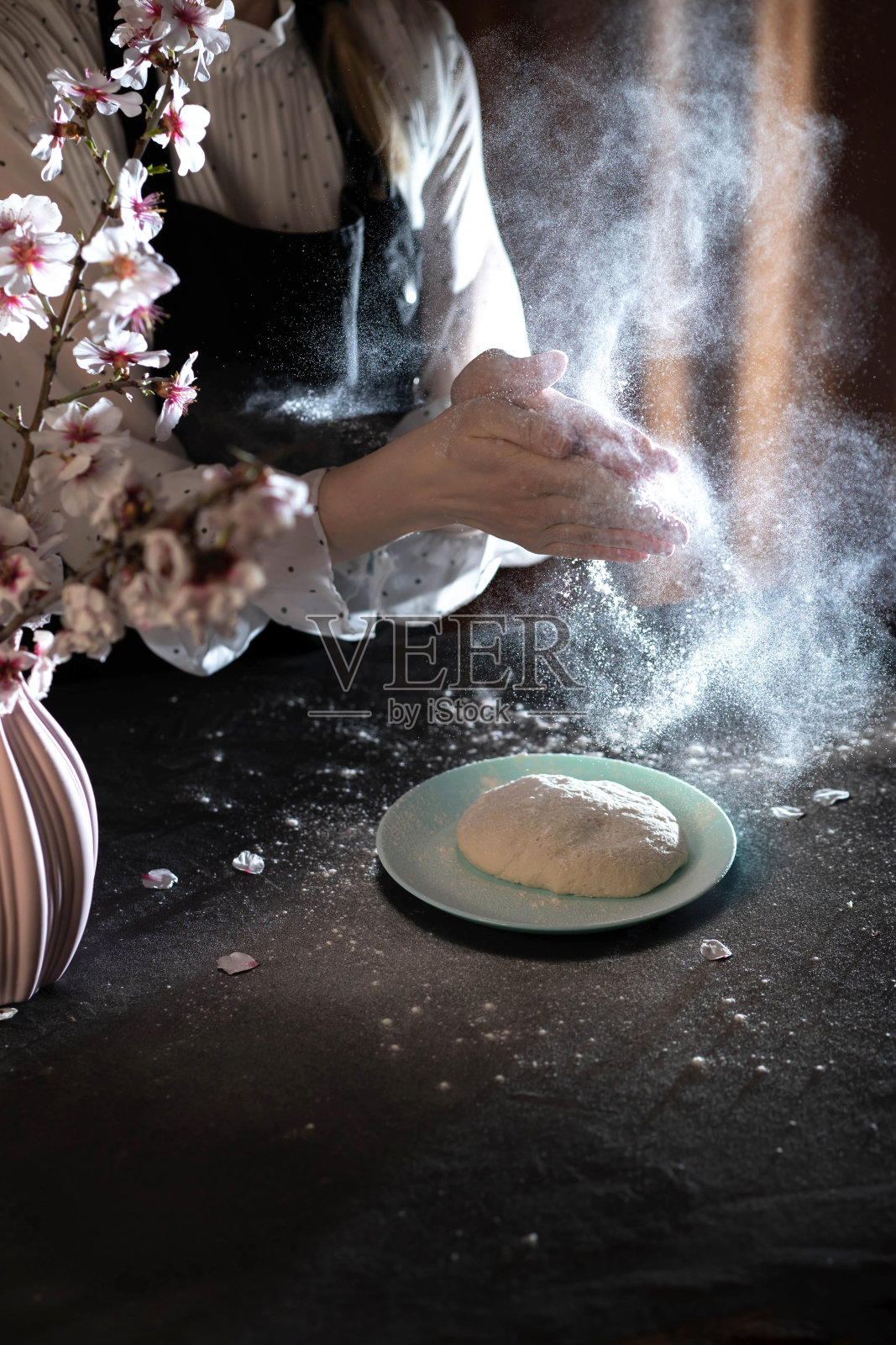 女人的手在桌上用面粉和配料揉面团。照片摄影图片