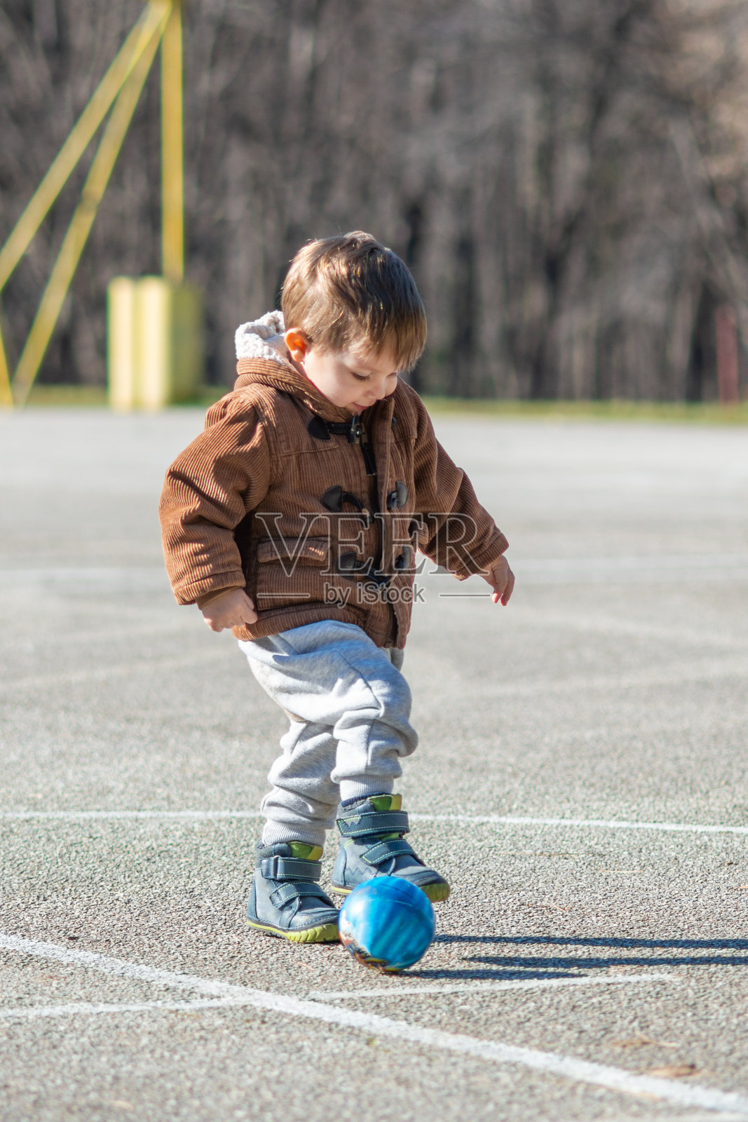 蹒跚学步的小男孩在操场上玩球照片摄影图片