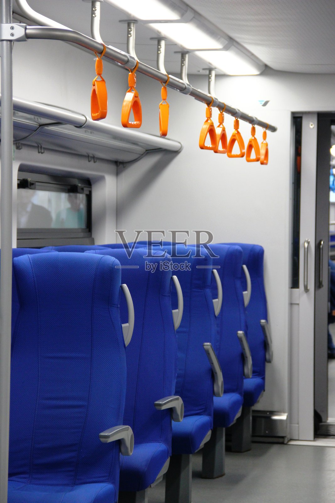 电动火车车厢里空荡荡的蓝色椅子和橙色的扶手。空的城市地铁车厢，直立照片摄影图片