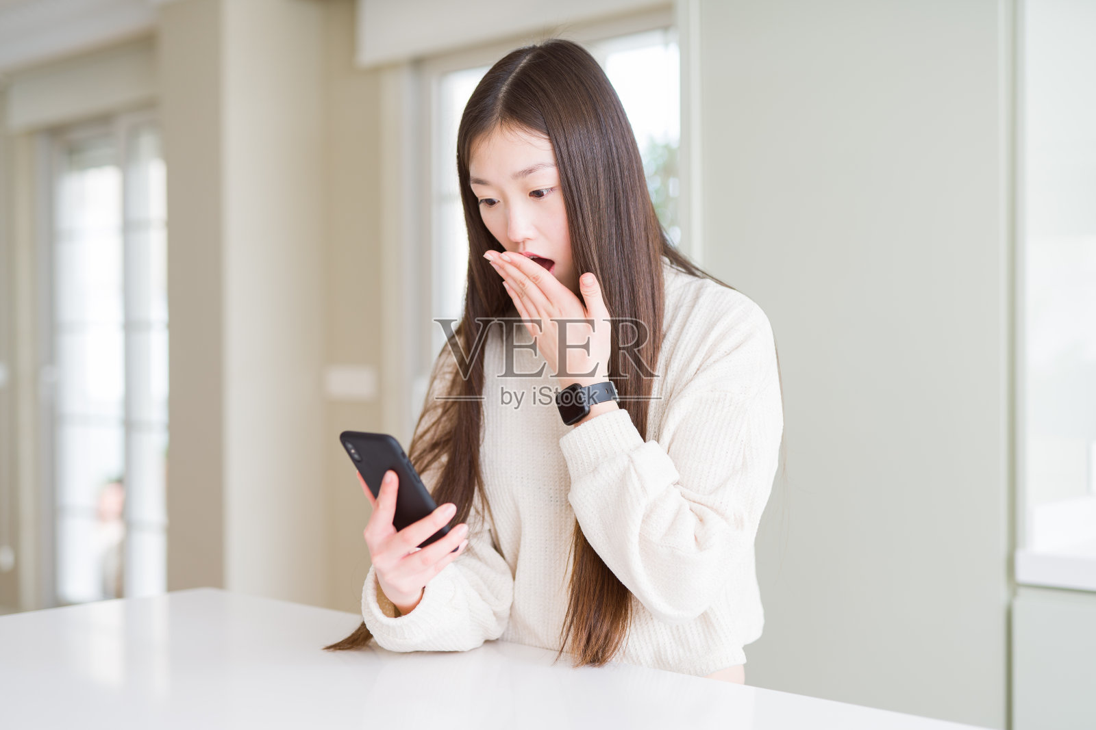 美丽的亚洲女人用智能手机捂住嘴用手为错误而震惊羞愧，表达恐惧，在沉默中害怕，秘密的概念照片摄影图片