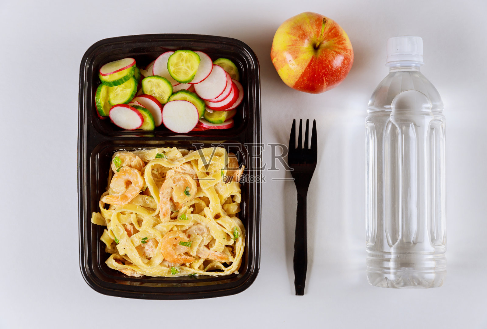 装在盛有水和苹果的食物容器上的即食食品。照片摄影图片