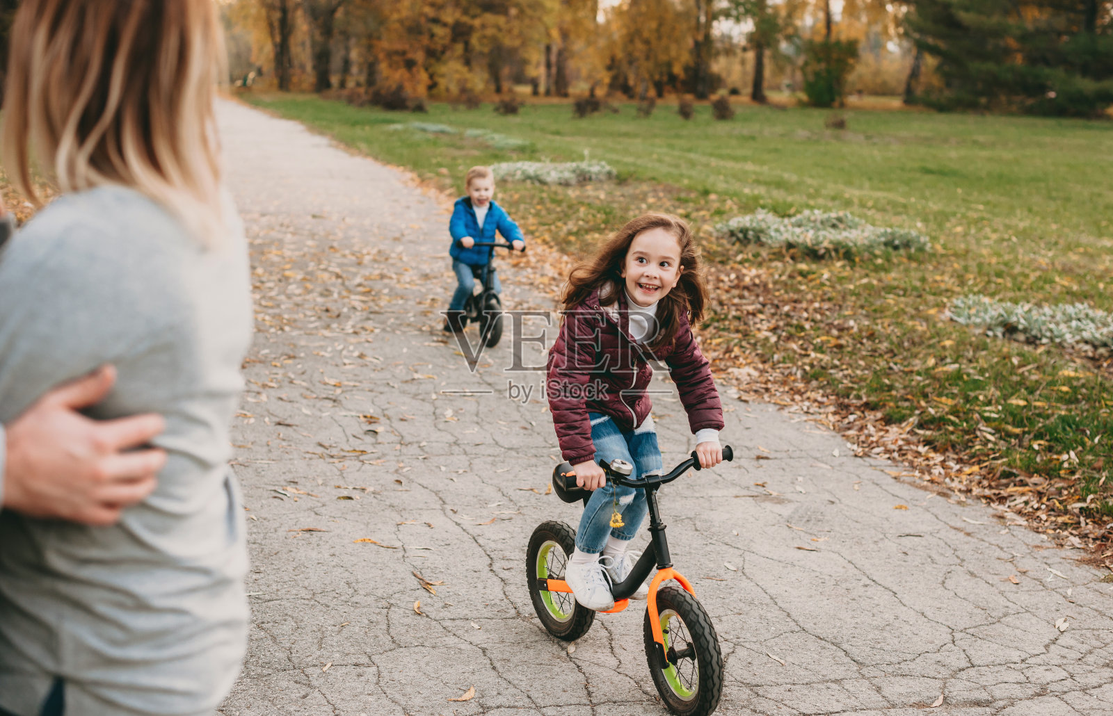 白种人的孩子们骑着他们的自行车，和他们的父母一起在公园里散步照片摄影图片