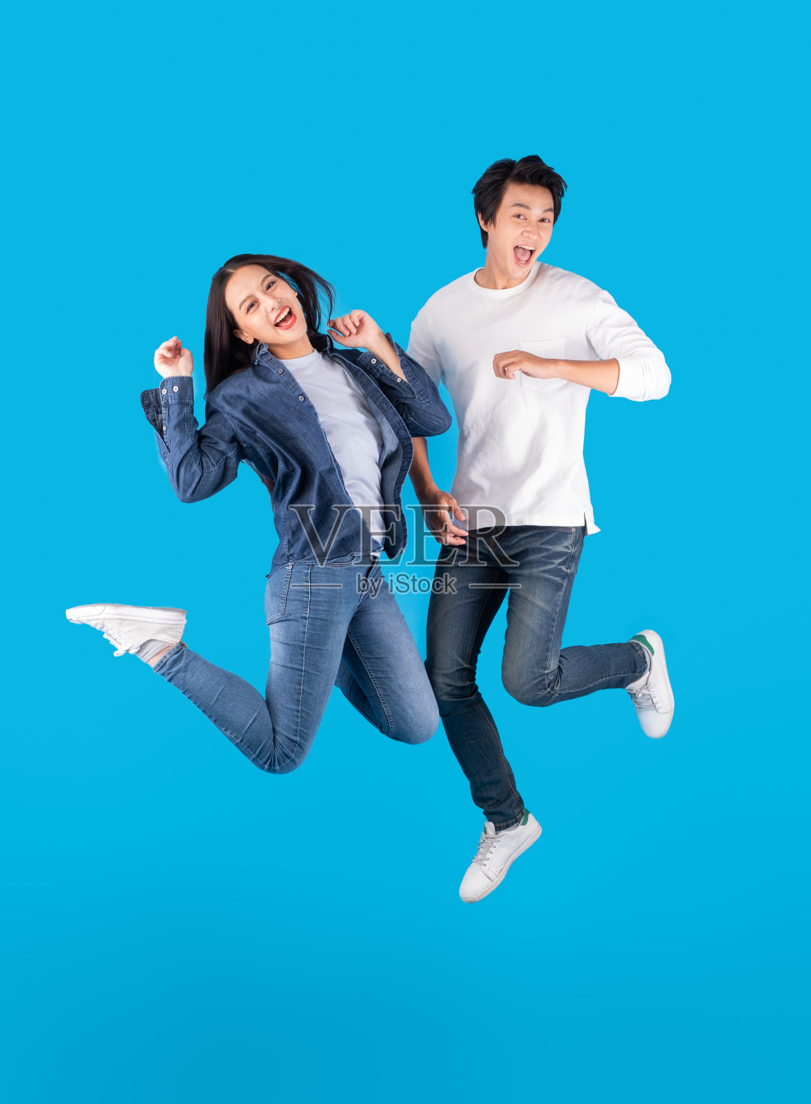 年轻的亚洲夫妇男人和女人跳跃与快乐和有趣的蓝色背景照片摄影图片