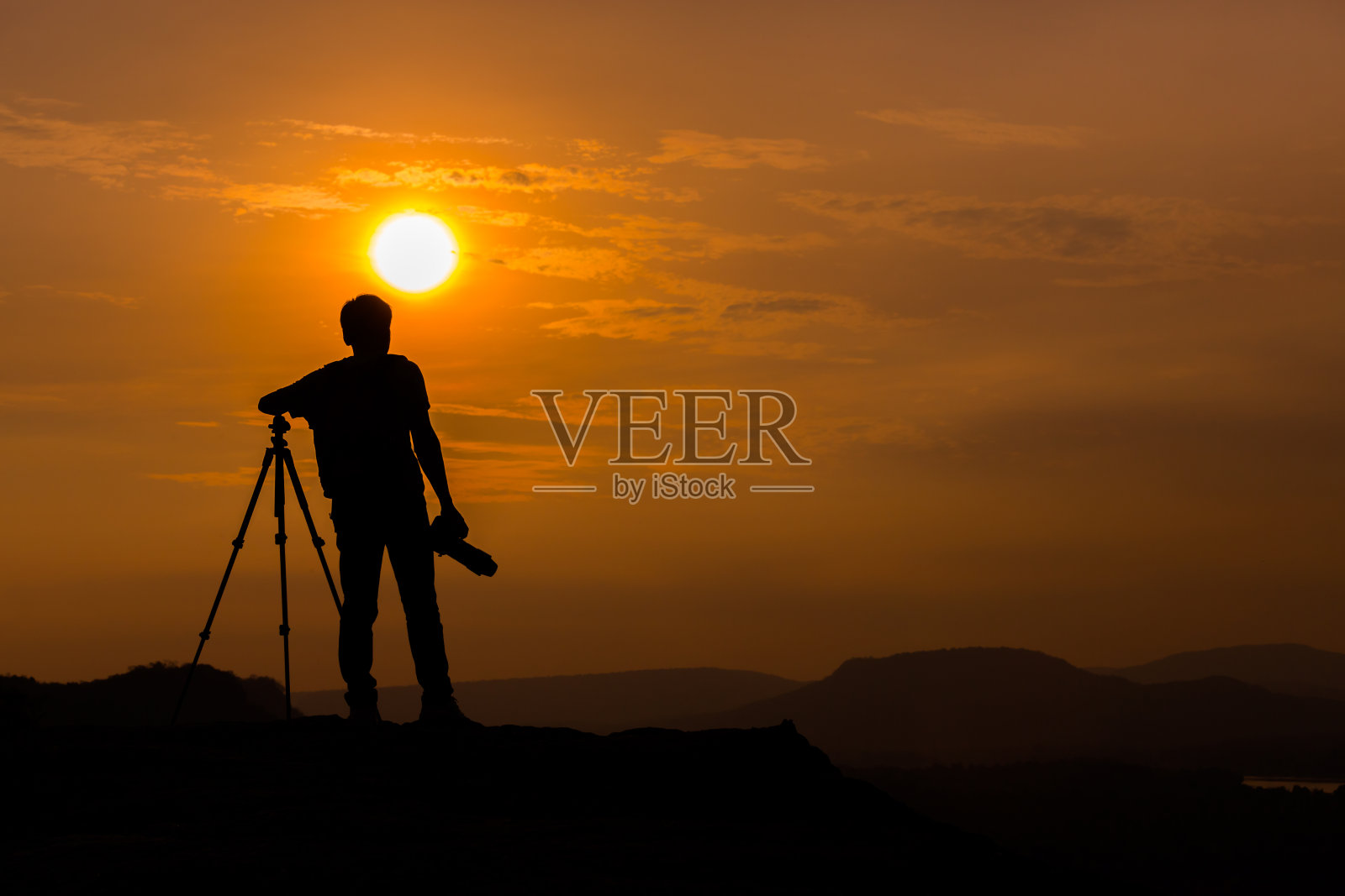 拍摄日落，摄影师在日落时上山照片摄影图片