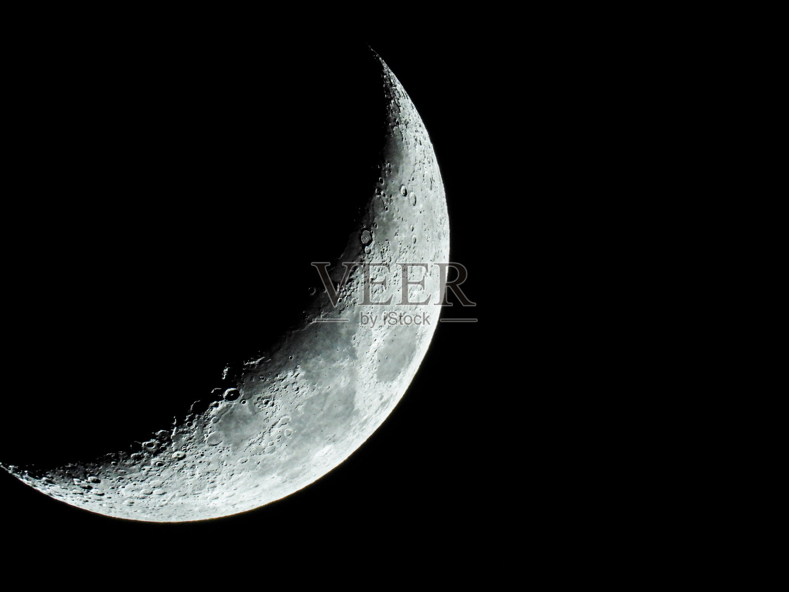 越来越多的镰刀形的四分之一的月亮和它的月亮坑站在黑暗的夜空照片摄影图片