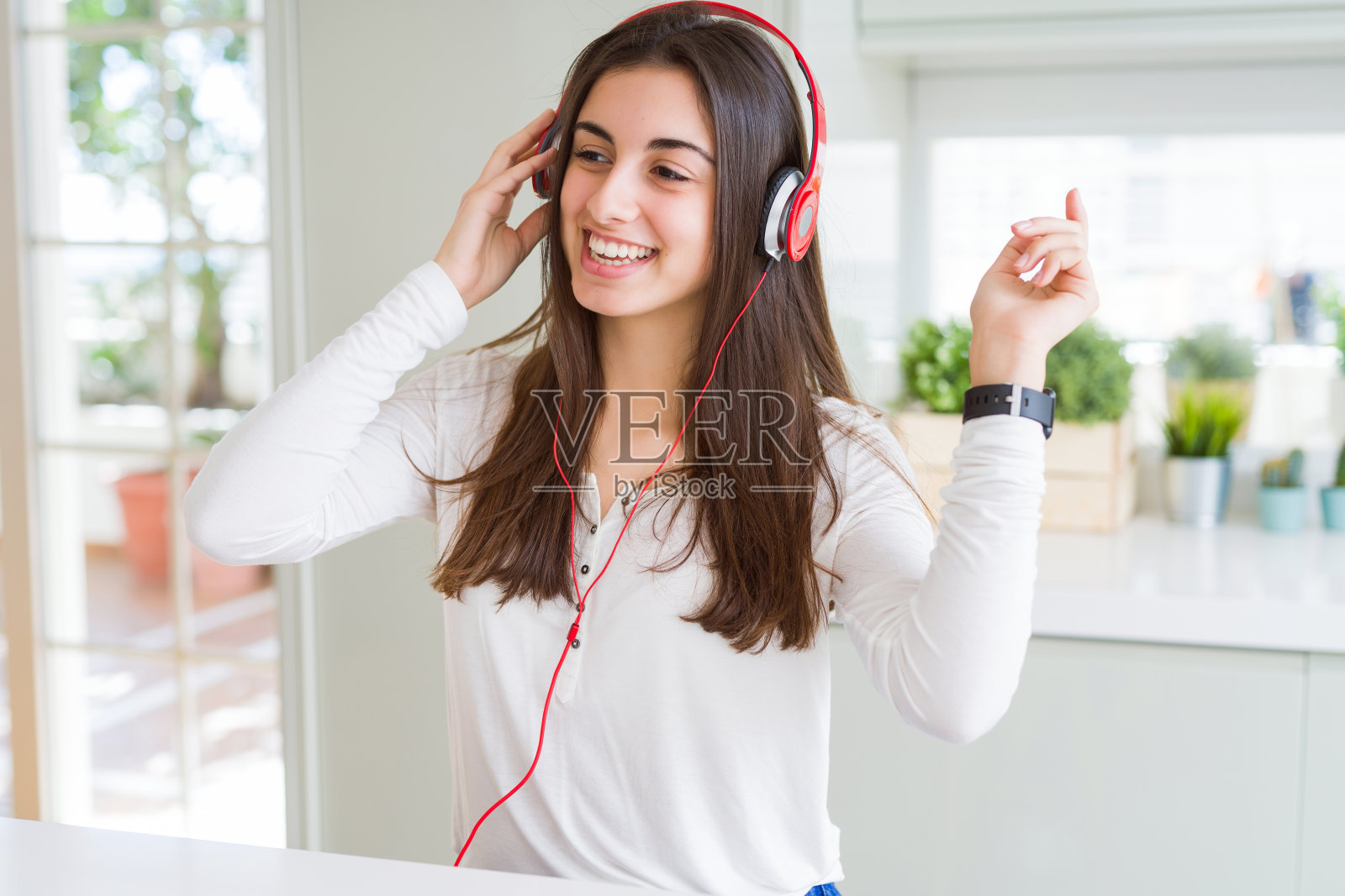 美丽的年轻女子戴着耳机听音乐，享受和跳舞的快乐照片摄影图片