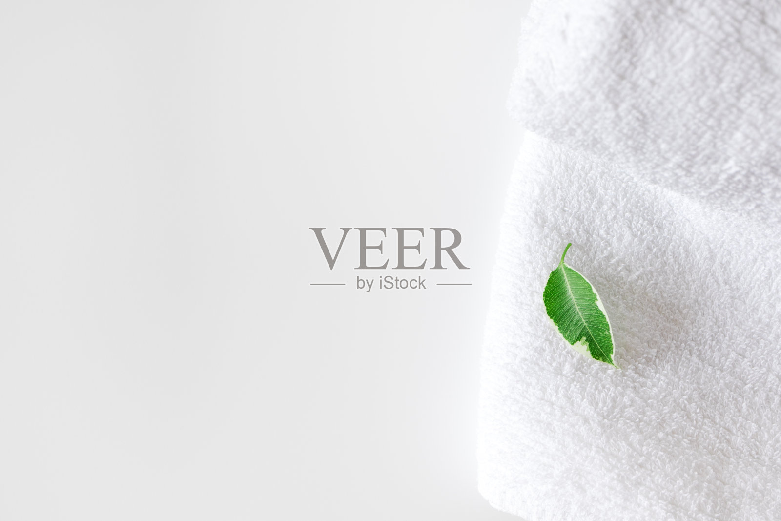 干净的浴巾和新鲜的绿叶在白色背景与复制空间和选择性焦点。概念保健水疗和卫生。国内的浴室,室内照片摄影图片