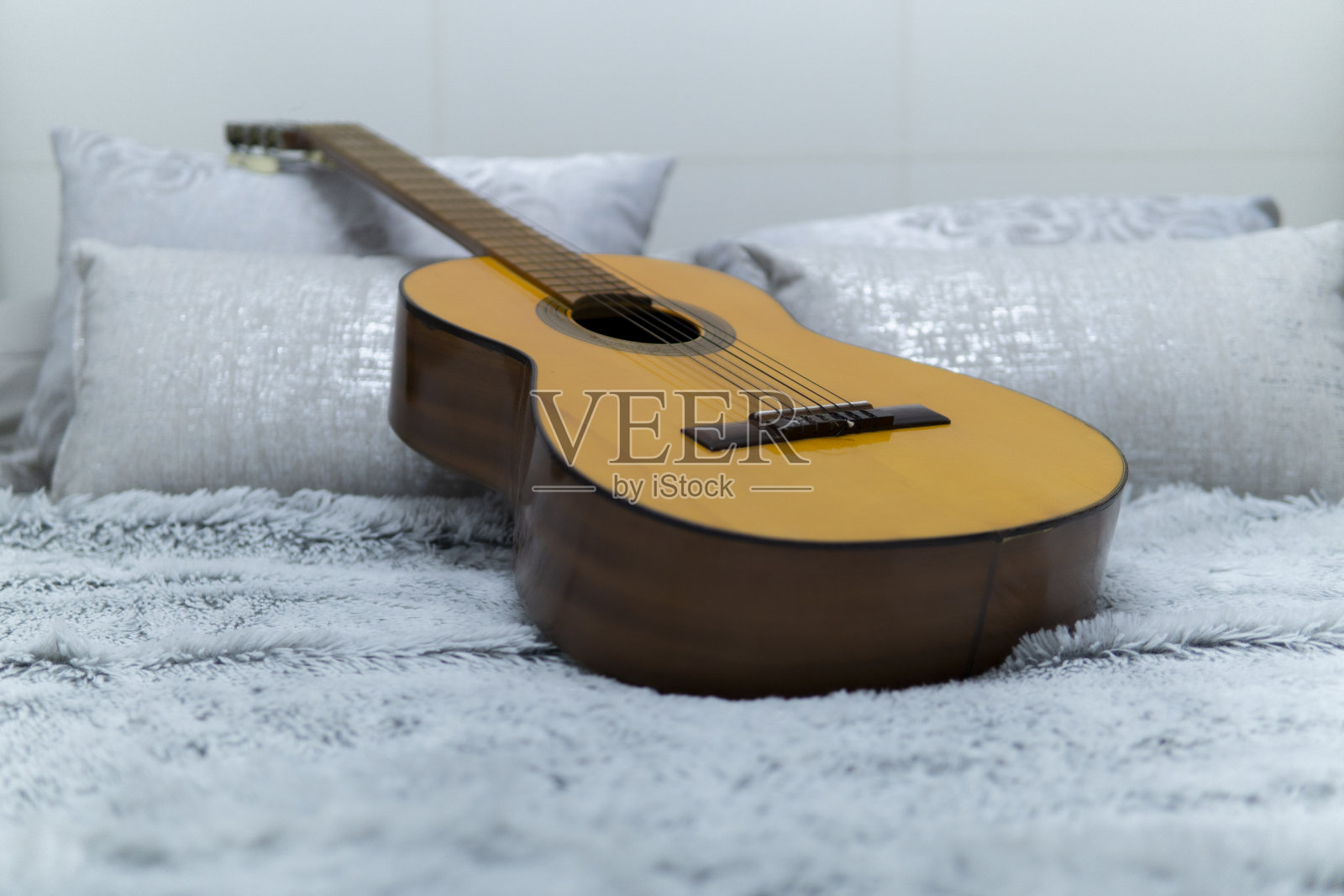 白色床上的西班牙吉他照片摄影图片