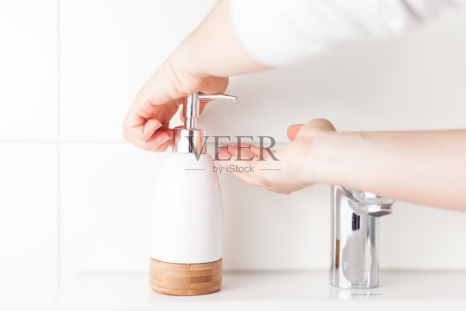 双手使用皂液器，涂抹肥皂液。照片摄影图片