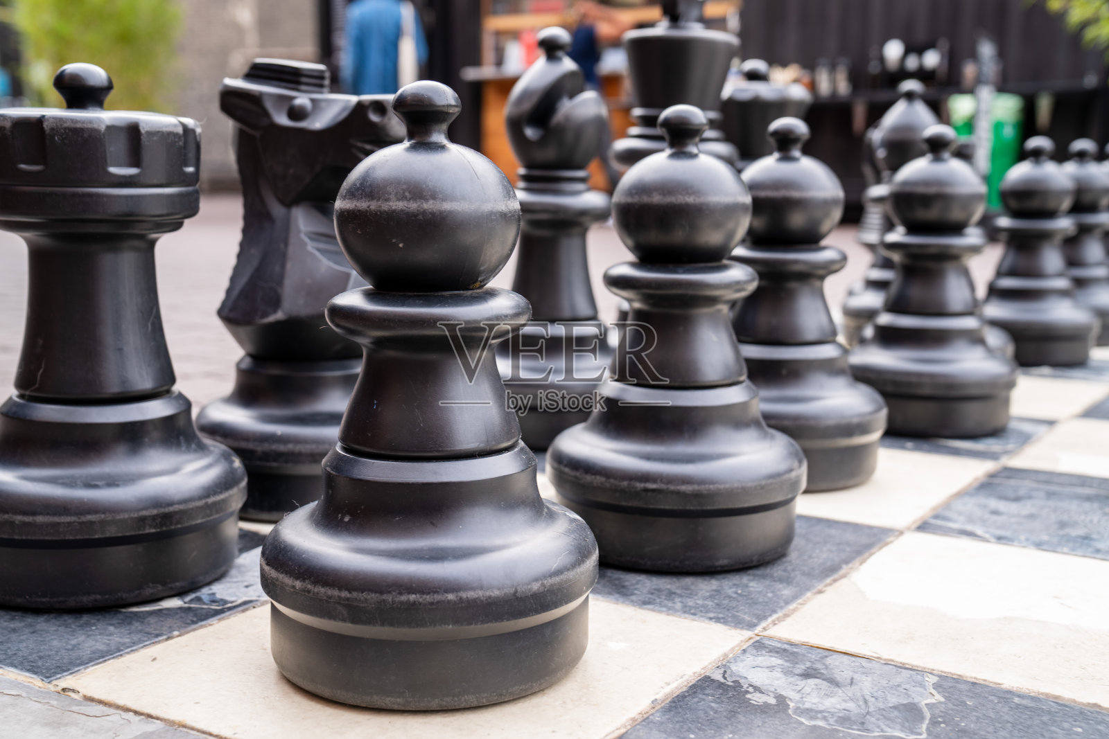 人类大小的黑棋棋子的近照，棋子在前面照片摄影图片