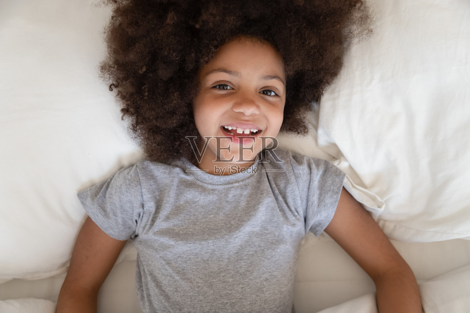 非洲小女孩躺在床上对着镜头微笑照片摄影图片