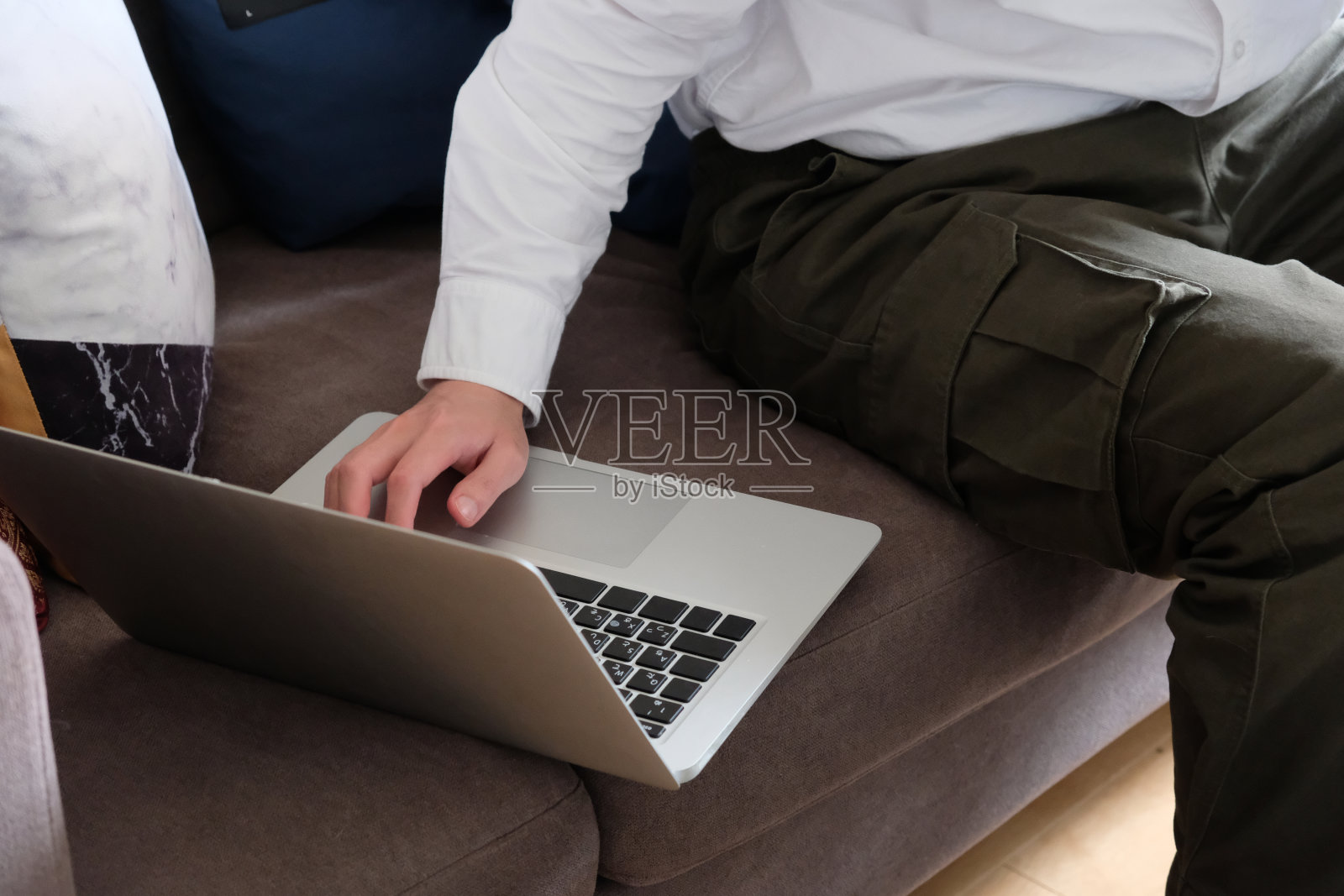商人的手在沙发上使用笔记本电脑。在家工作的概念照片摄影图片