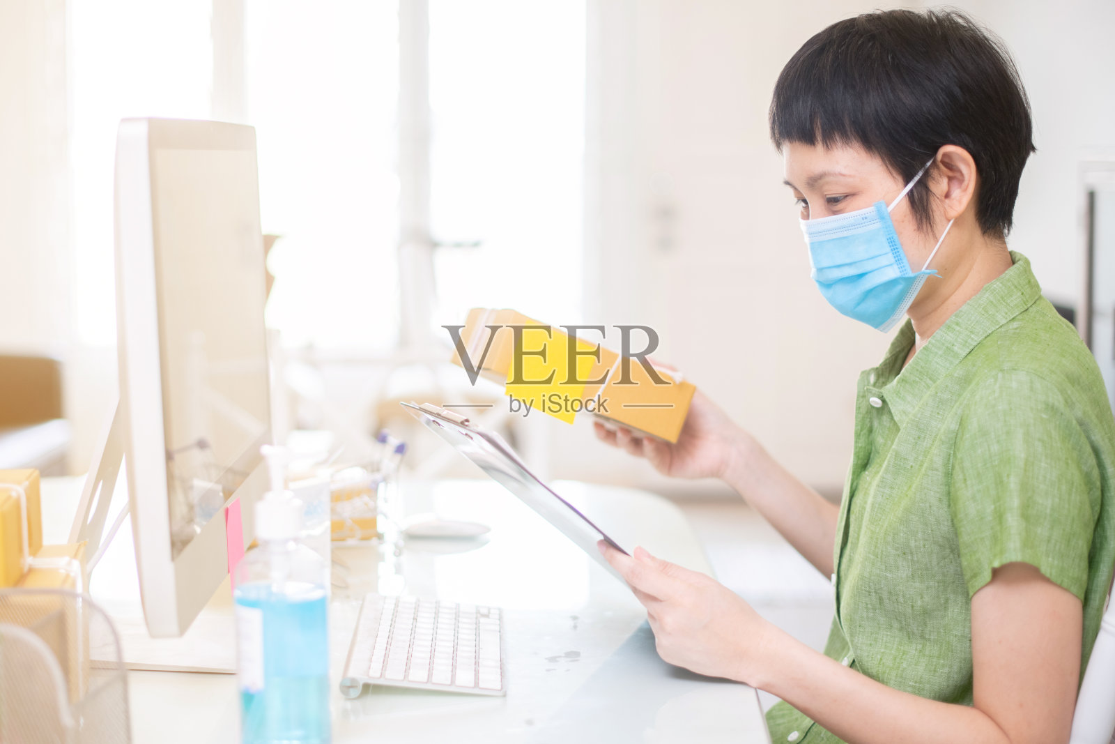 成功的亚洲在线商务女性戴着外科口罩和消毒凝胶。在冠状病毒或covid-19隔离期间在家工作照片摄影图片