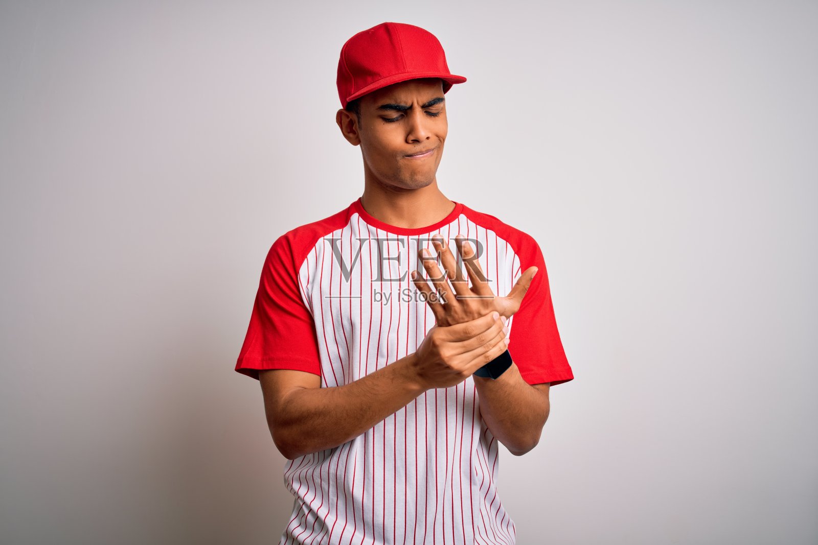 年轻英俊的非裔美国运动员穿着条纹棒球t恤和帽子手和手指痛苦，关节炎炎症照片摄影图片
