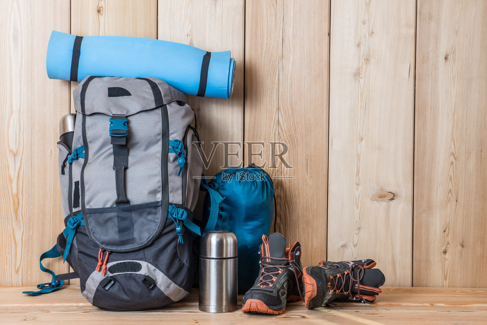 露营装备，鞋子，背包和一个保温瓶，木质背景照片摄影图片