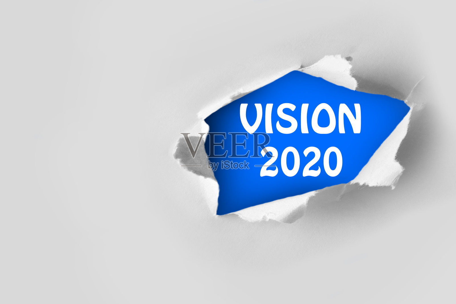 写在一张破纸后面的2020愿景目标。顶部视图的白色撕下的纸和文字“愿景2020”在一个蓝色的背景。照片摄影图片