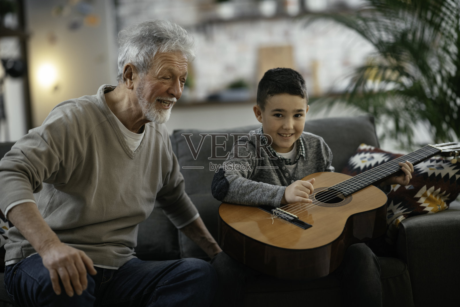 爷爷和孙子在弹吉他。照片摄影图片