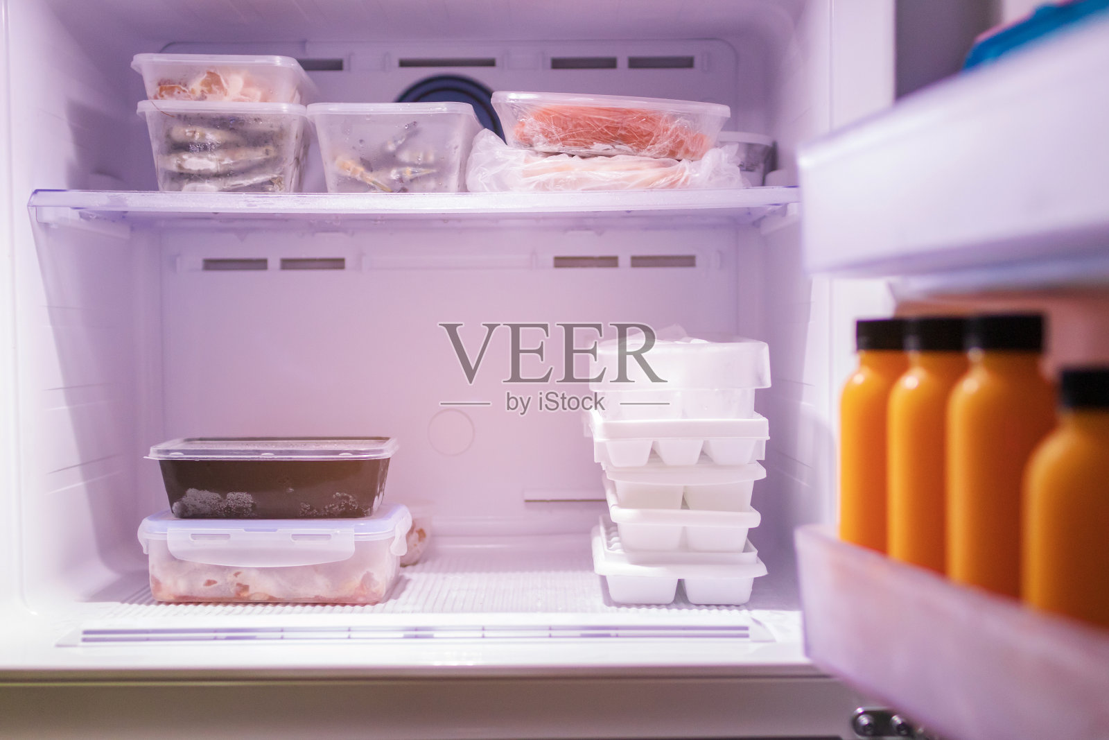 冰箱里的冷冻食品。肉类，海鲜，果汁和冰在冰箱的架子上。股票的一餐。照片摄影图片