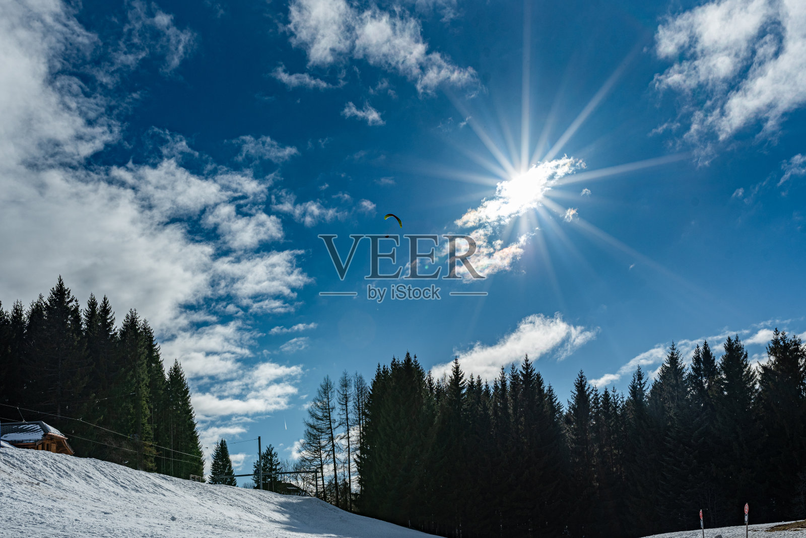 降落伞有阳光，蓝天，白云，树木和雪。照片摄影图片