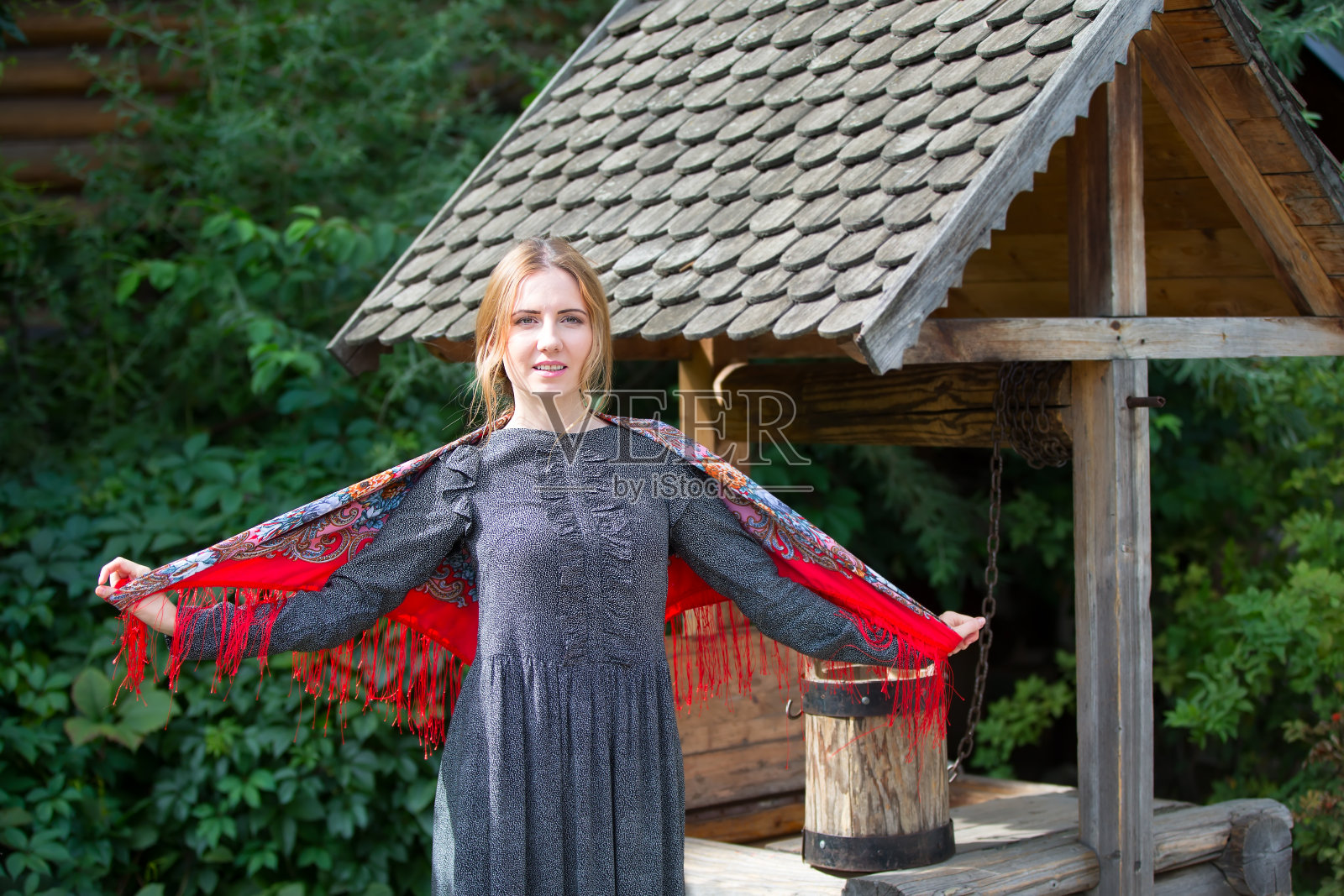 一个围着围巾拿着桶在井边的俄罗斯女人。俄罗斯女人。一个拿着俄罗斯手帕的女人。照片摄影图片