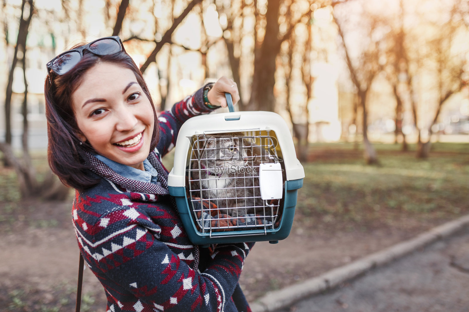 一位妇女正用特制的塑料笼子或提包运送一只猫到兽医诊所照片摄影图片