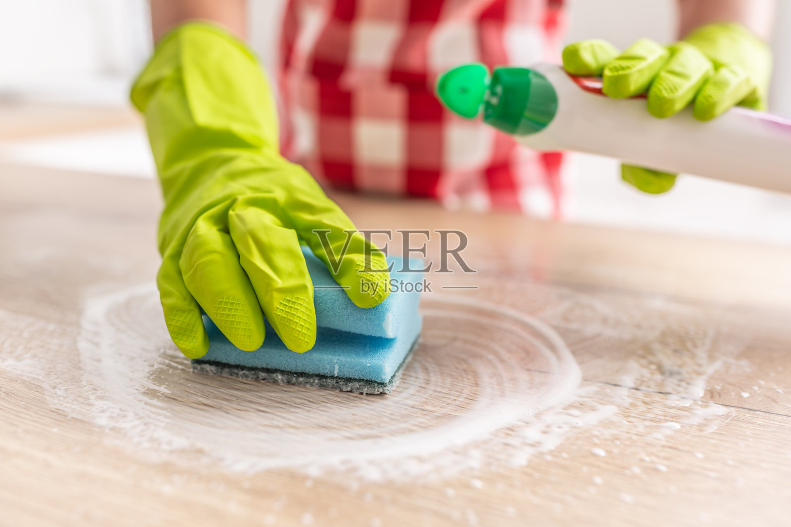 一只手戴着橡胶手套，用蓝色海绵用洗涤剂清洁表面。照片摄影图片