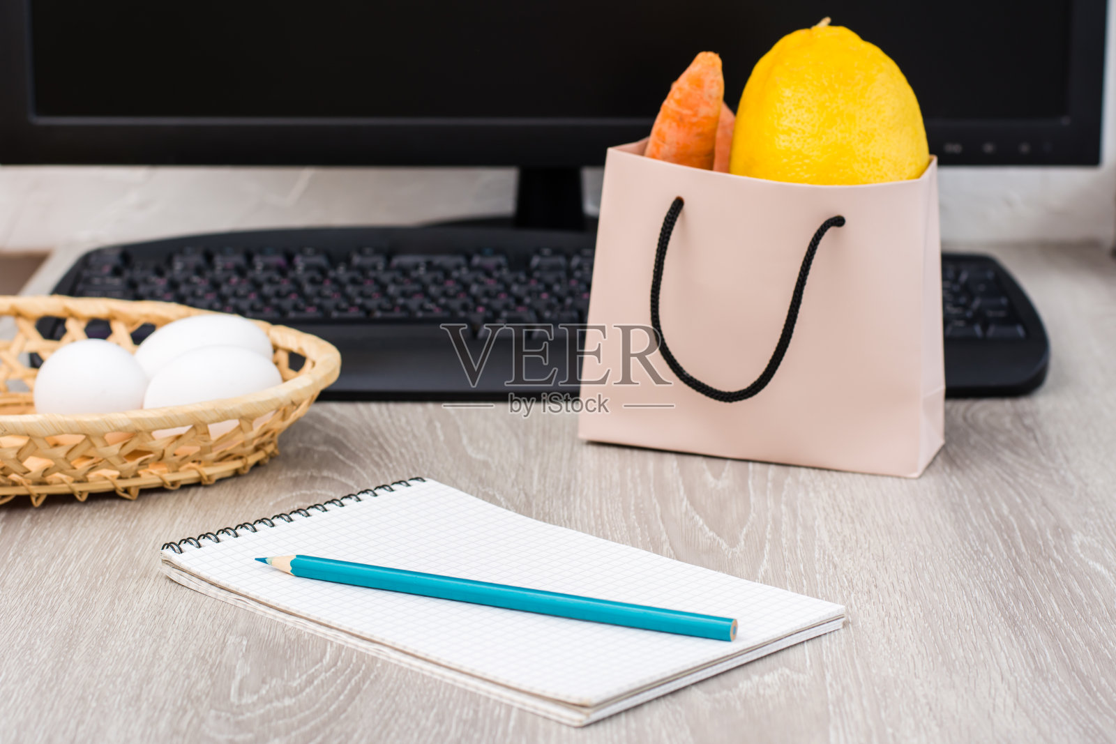足不出户就能在网上购物的概念。一个购物清单的笔记本，背景是一个篮子，一个键盘和一袋食物在桌子上。照片摄影图片