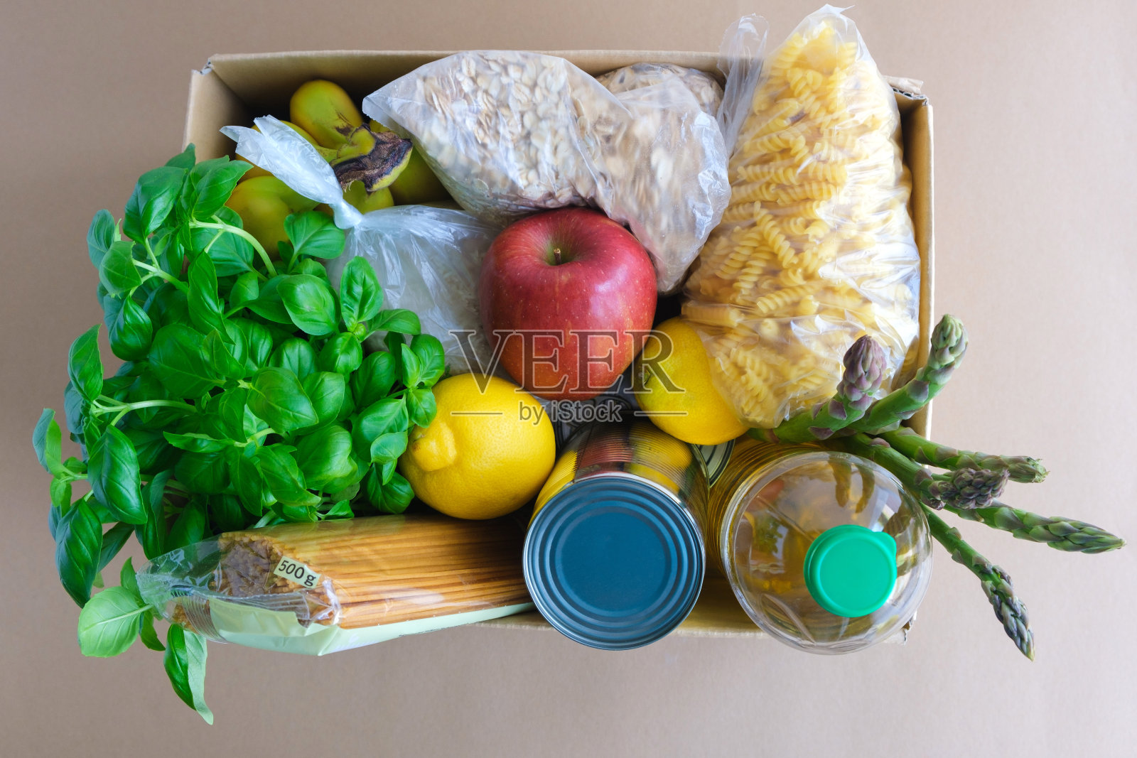 顶视图上的纸板盒与产品。香蕉、柠檬、苹果、意大利面、燕麦片、大米、罗勒、葵花籽油和罐头食品。食物捐赠照片摄影图片